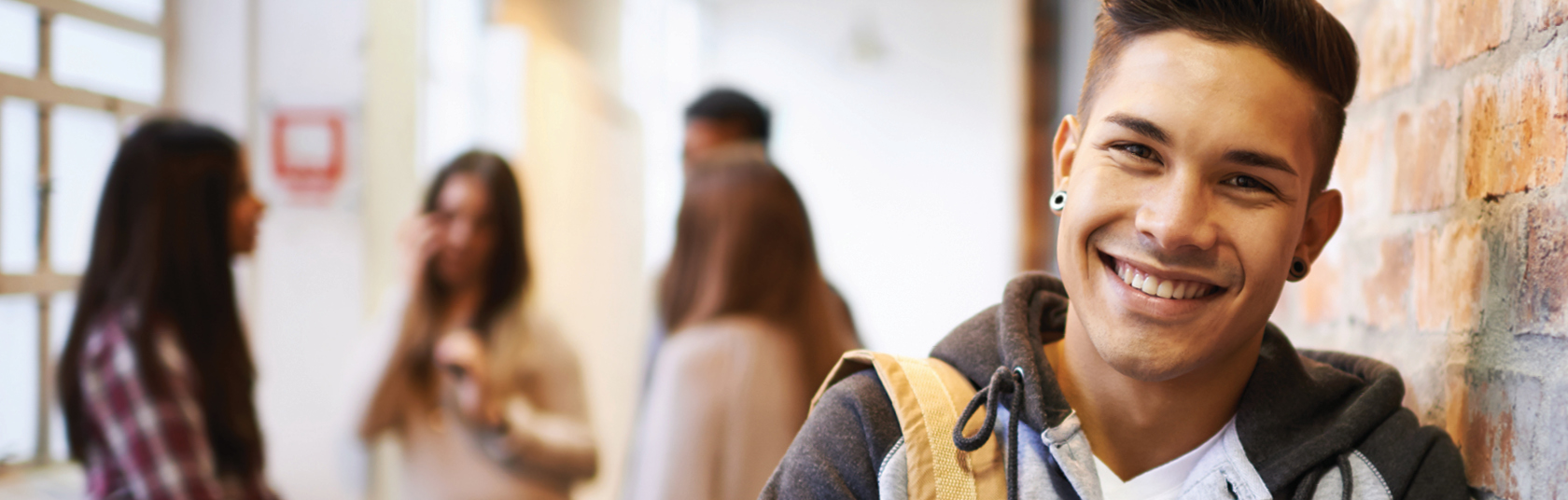 Student leaning against a wall with a group of students in the background